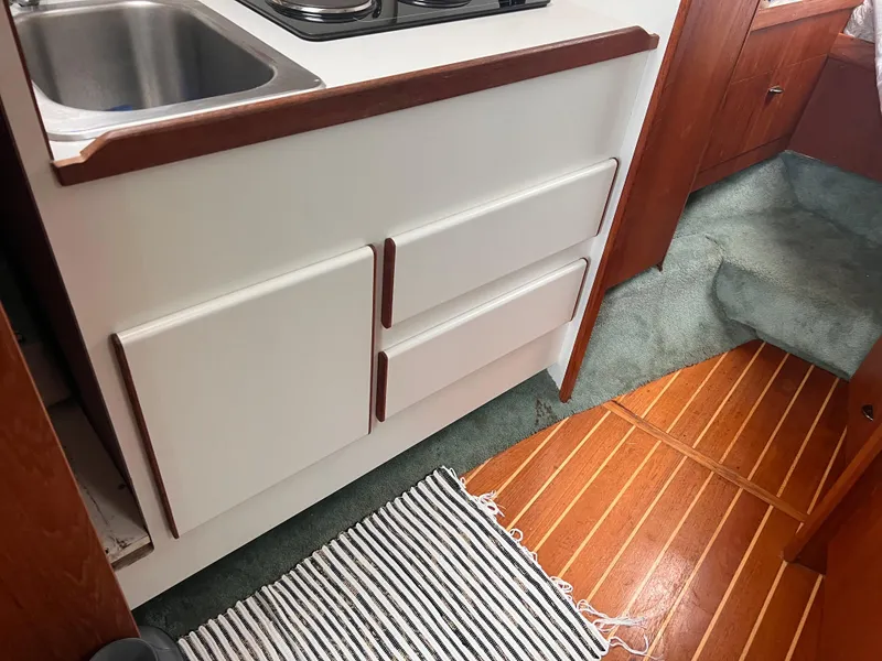 Slide: The Image of 1996 Pursuit 3100 Open boat interior with kitchenette, sink, and wooden flooring. - 12