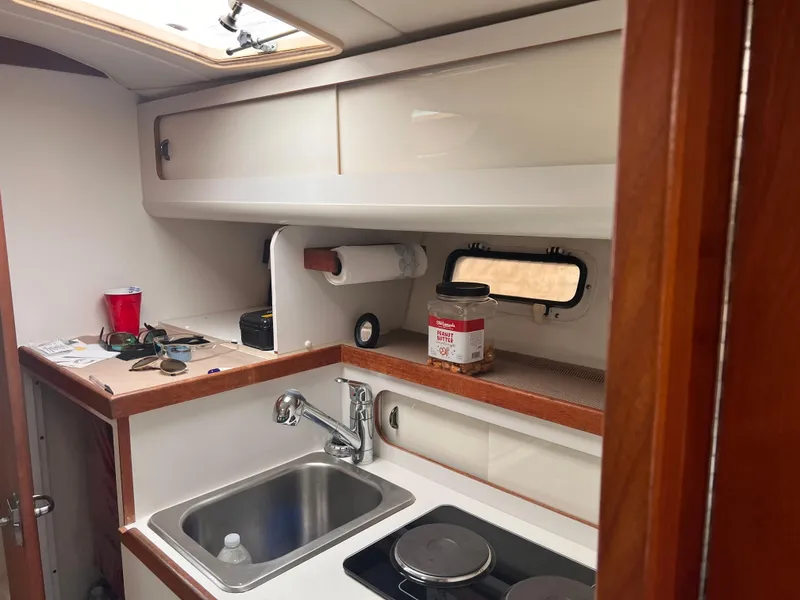 Slide: The Image of 1996 Pursuit 3100 Open boat kitchen with sink, stove, and storage cabinets. - 17