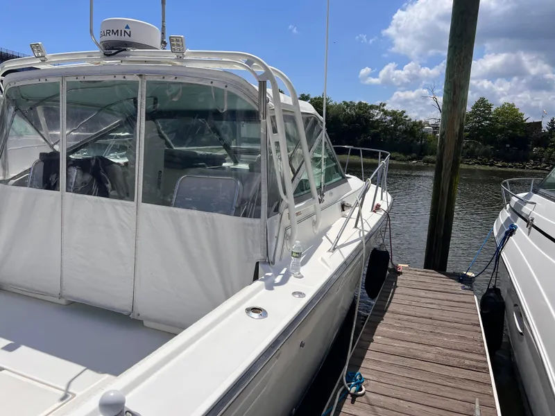 Slide: The Image of 1996 Pursuit 3100 Open boat docked, featuring Garmin equipment, under a clear blue sky. - 2