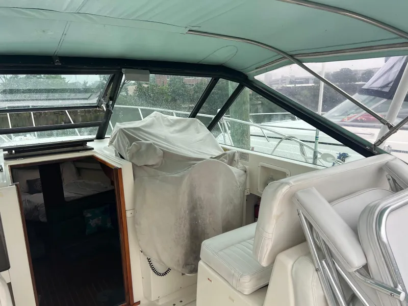 Slide: The Image of 1996 Pursuit 3100 Open boat interior with covered seating and helm, docked on a rainy day. - 23