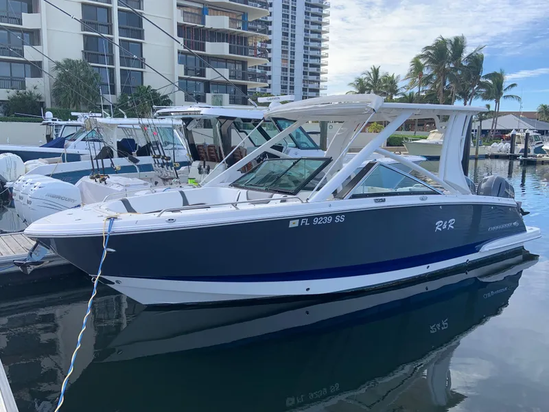 Slide: The Image of 2020 Chaparral 280 OSX boat docked in a marina with modern buildings in the background. - 1