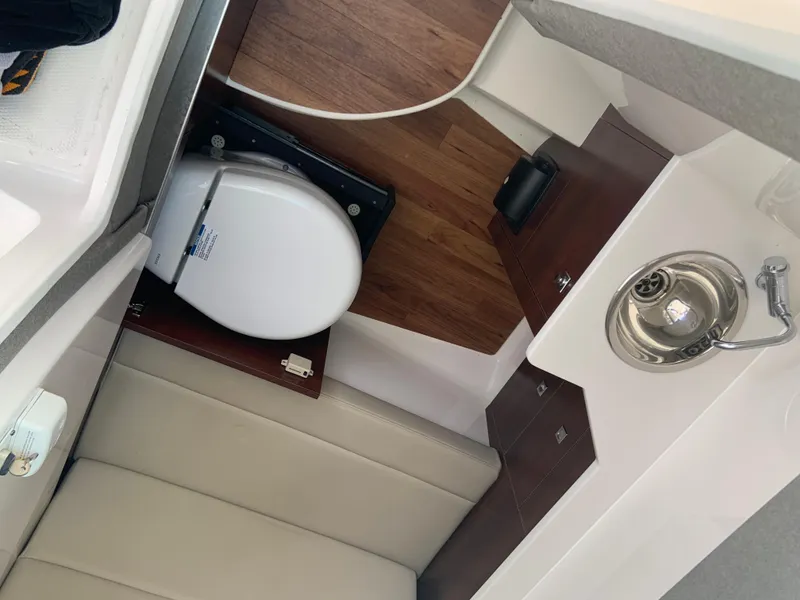 Slide: The Image of 2020 Chaparral 280 OSX boat interior with toilet, sink, and wooden flooring. - 21