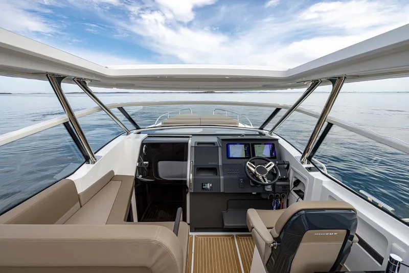 Slide: The Image of Interior view of 2025 Nimbus W11 boat, featuring modern helm and seating, overlooking calm waters. - 3