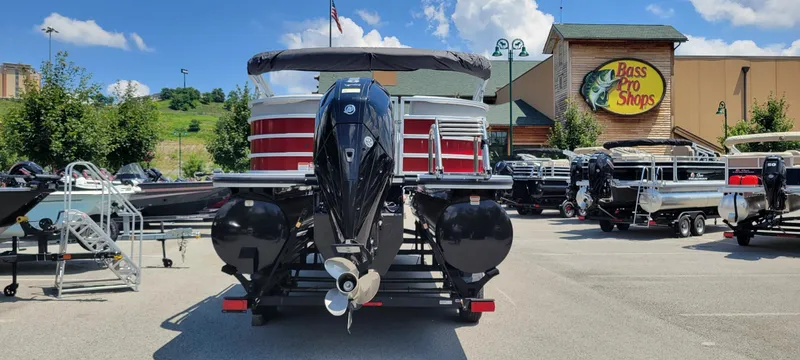 Slide: The Image of 2024 Ranger Reata 243C pontoon boat displayed at Bass Pro Shops parking lot. - 2