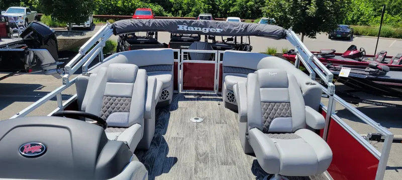 Slide: The Image of 2024 Ranger Reata 243C pontoon boat with plush seating and modern design in a sunny outdoor setting. - 5