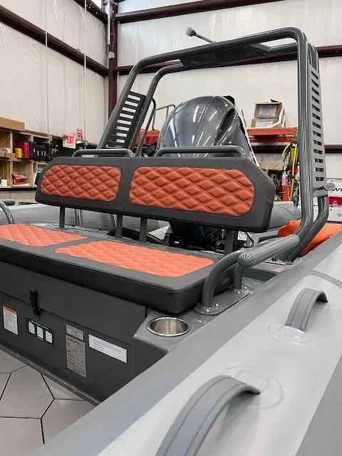 Slide: The Image of 2024 Highfield Sport 660 boat with orange cushioned seats in a warehouse. - 7