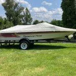 Slide: The Image of 1993 American Skier Legend boat on trailer with cover, parked on grassy field. - 11