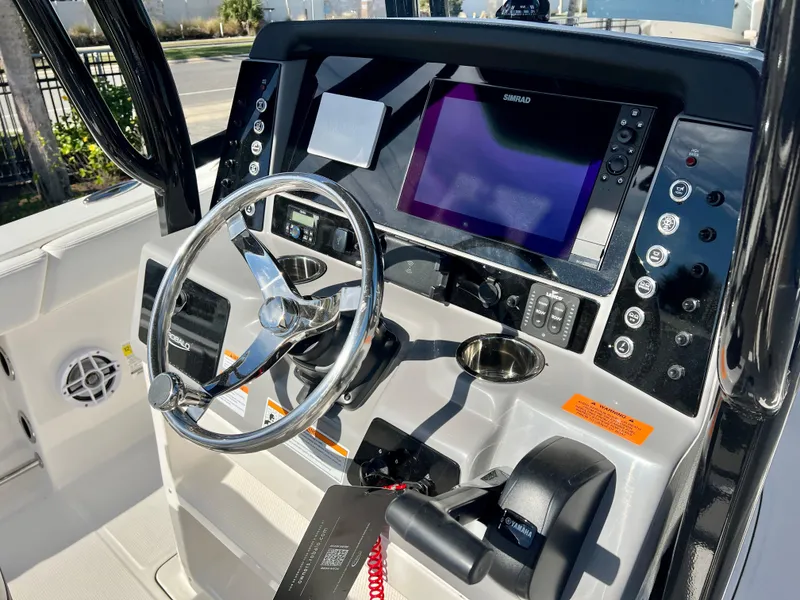 Slide: The Image of 2024 Robalo R230 boat dashboard with steering wheel, Simrad display, and control panel. - 17