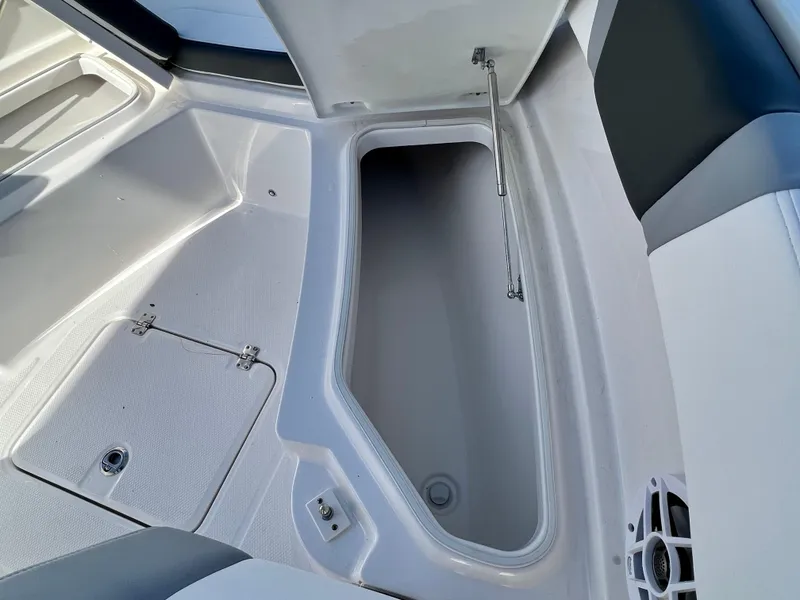 Slide: The Image of 2024 Robalo R230 boat storage compartment with open hatch and cushioned seating. - 26