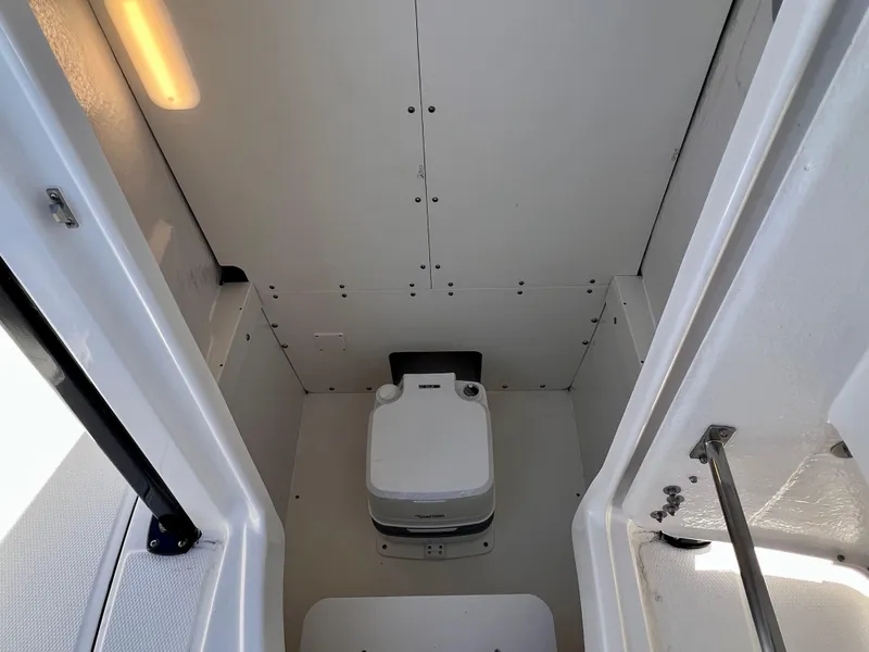 Slide: The Image of 2024 Robalo R230 boat interior with a compact marine toilet. - 31