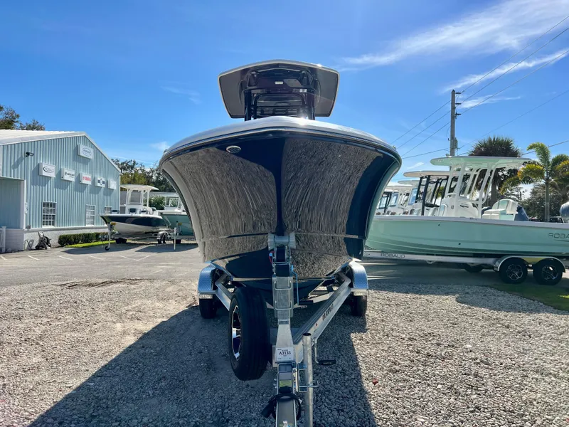 Slide: The Image of 2024 Robalo R230 boat on trailer at dealership under clear blue sky. - 6