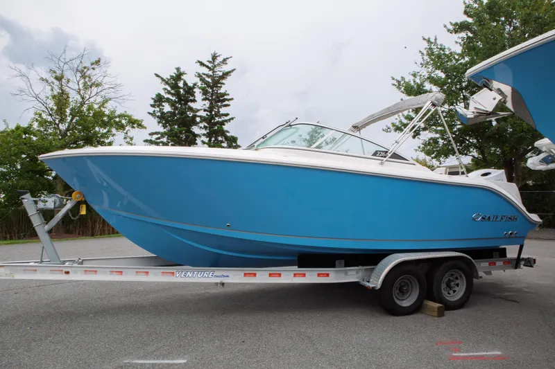 The Image of 2024 Sailfish 226 DC boat in blue on a trailer, parked outdoors. - 0