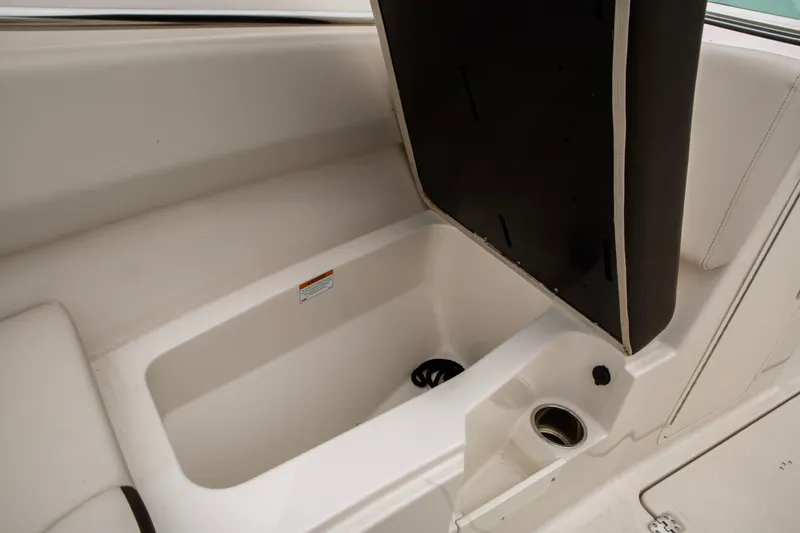Slide: The Image of 2024 Sailfish 226 DC boat storage compartment with open lid and cup holder. - 15
