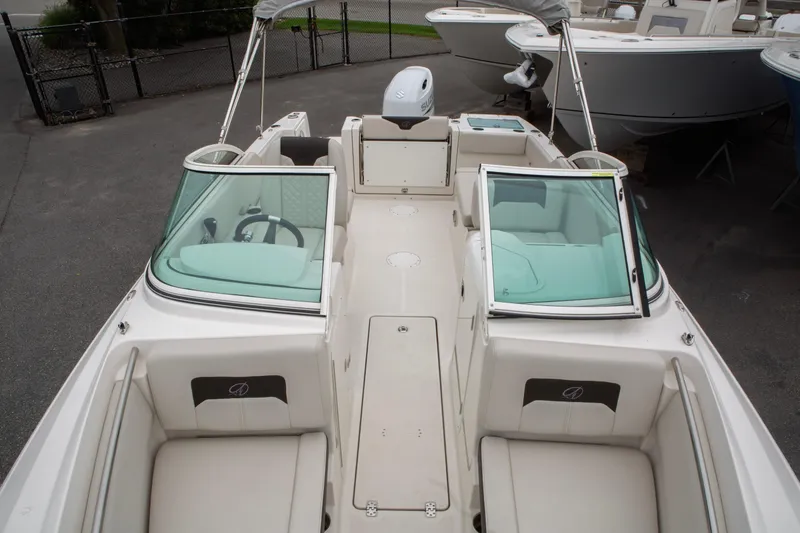 Slide: The Image of 2024 Sailfish 226 DC boat interior with seating and steering wheel, docked outdoors. - 17