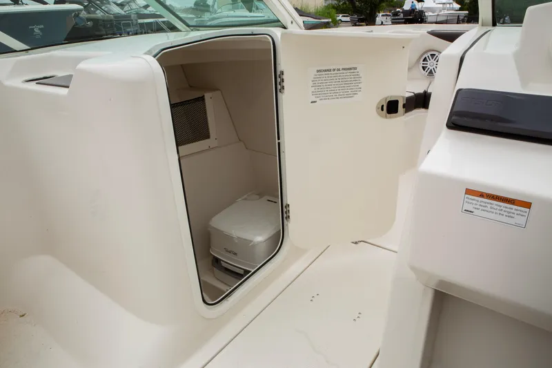 Slide: The Image of 2024 Sailfish 226 DC boat interior with open storage compartment and portable toilet. - 21