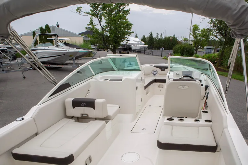 Slide: The Image of 2024 Sailfish 226 DC boat interior with seating and steering console, parked outdoors. - 30
