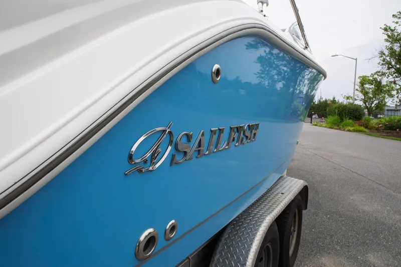 Slide: The Image of 2024 Sailfish 226 DC boat, blue hull, parked on trailer, side view. - 33
