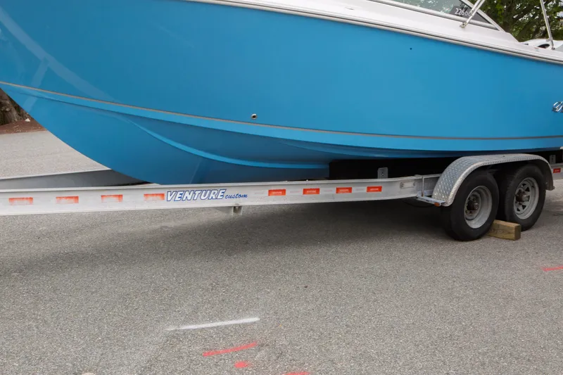 Slide: The Image of 2024 Sailfish 226 DC boat on Venture trailer, parked on pavement. - 36