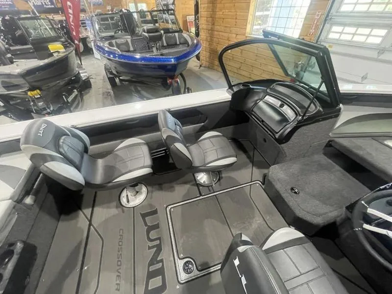 Slide: The Image of 2024 Lund Crossover XS 1875 boat interior with seating and dashboard in showroom. - 17