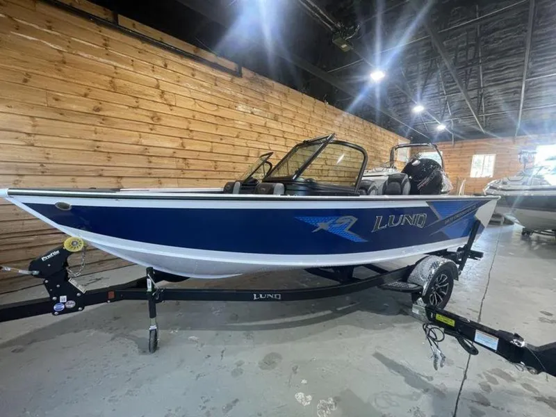 Slide: The Image of 2024 Lund Crossover XS 1875 boat in showroom, blue and white exterior, on trailer. - 3