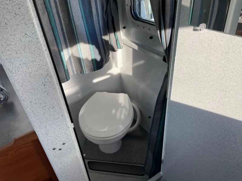 Slide: The Image of 2024 KingFisher 2725 Weekender boat bathroom with compact toilet and privacy curtain. - 17