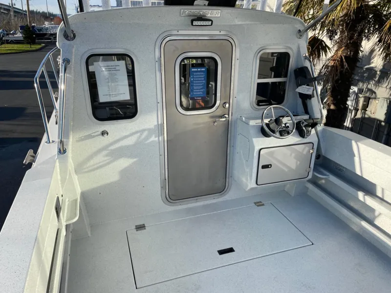 Slide: The Image of 2024 KingFisher 2725 Weekender boat cockpit with steering wheel and cabin door. - 5