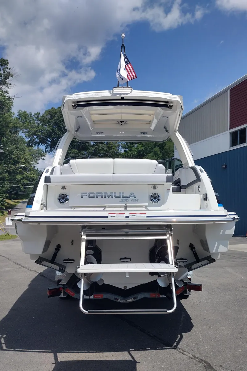 Slide: The Image of 2026 Formula 330 CBR boat, rear view, docked with American flag, sunny day. - 10