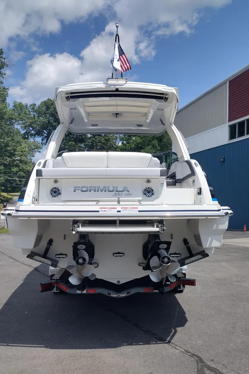 Slide: The Image of 2026 Formula 330 CBR boat, rear view, docked outdoors under a partly cloudy sky. - 13