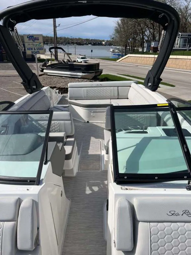 Slide: The Image of 2024 Sea Ray SDX 270 boat interior with seating and windshield, docked near a lake. - 9