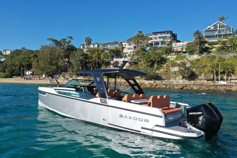 Slide: The Image of 2024 Saxdor 320 GTO luxury motorboat cruising near a scenic coastal area. - 2