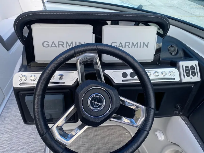 Slide: The Image of 2024 Crownline 250 XSS boat dashboard with dual Garmin displays and modern steering wheel. - 13
