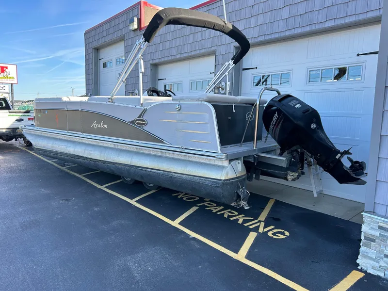 Slide: The Image of 2014 Avalon 2285 Catalina Cruise Twin Toon pontoon boat parked outside a garage. - 4
