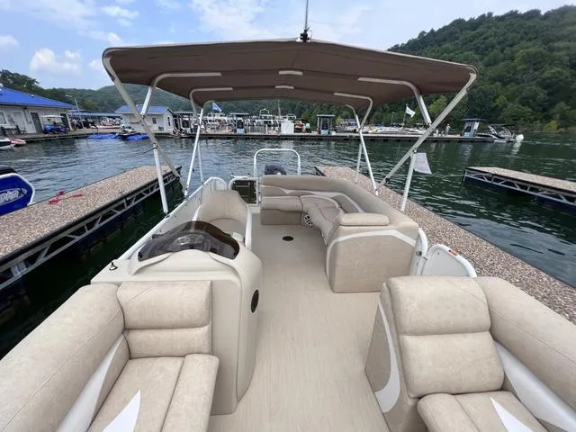 Slide: The Image of 2024 Aloha 230 Club Series boat with beige seating, docked at a marina. - 13