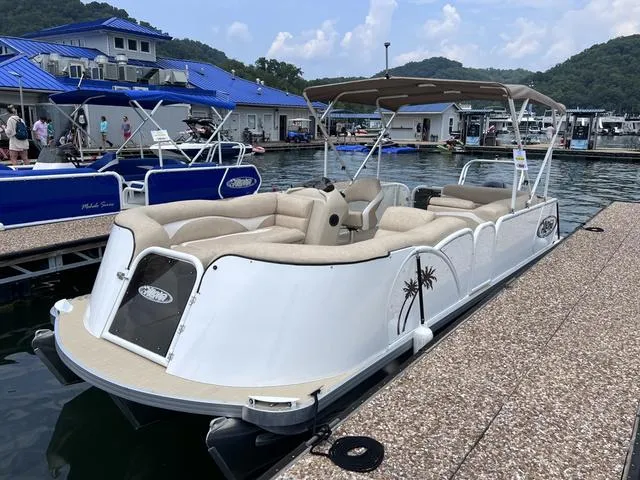 Slide: The Image of 2024 Aloha 230 Club Series pontoon boat docked at a marina with scenic background. - 5