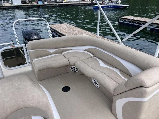 Slide: The Image of 2024 Aloha 230 Club Series boat with beige seating, docked by the water. - 8