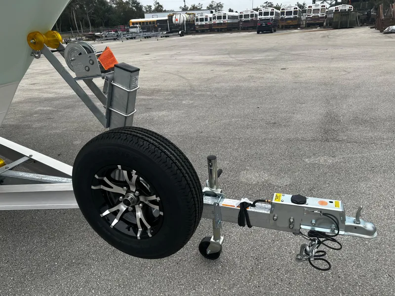Slide: The Image of 2024 Pioneer 220 Bay Sport boat trailer hitch and wheel on asphalt. - 34