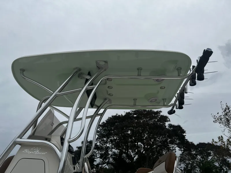 Slide: The Image of 2024 Pioneer 220 Bay Sport boat with T-top and rod holders against cloudy sky. - 40