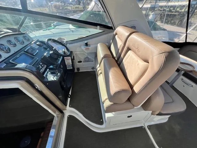 Slide: The Image of 2017 Sea Ray 330 Sundancer helm with beige seating and modern dashboard controls. - 10