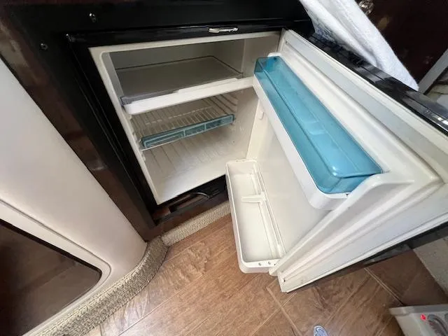 Slide: The Image of Open refrigerator inside 2017 Sea Ray 330 Sundancer boat, showing interior shelves and door storage. - 20