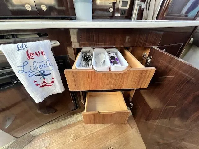 Slide: The Image of Kitchen drawers in a 2017 Sea Ray 330 Sundancer yacht, with utensils and a decorative towel. - 21
