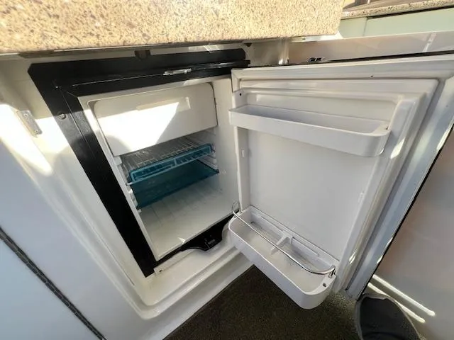 Slide: The Image of Open refrigerator on 2017 Sea Ray 330 Sundancer boat, showing interior shelves and door compartments. - 7