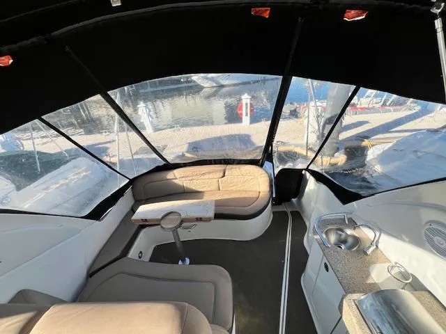 Slide: The Image of 2017 Sea Ray 330 Sundancer interior with seating, table, and kitchenette under a black canopy. - 8