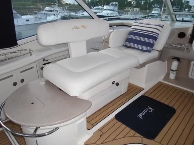 Slide: The Image of 2005 Sea Ray 500 Sundancer interior with white seating and striped pillow, docked at marina. - 23