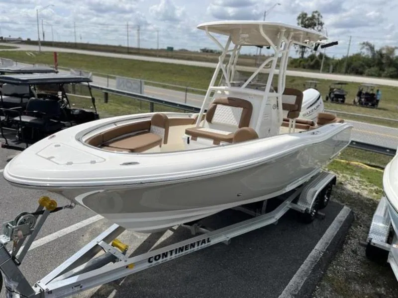 Slide: The Image of 2024 Pioneer Islander 222 boat on trailer, white with brown seating, parked outdoors. - 23