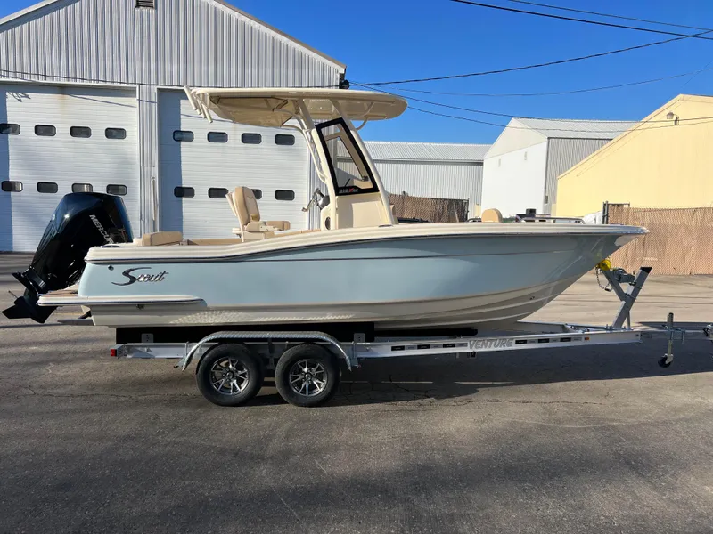 Slide: The Image of 2024 Scout 215 XSF boat on trailer, parked outside industrial building. - 8