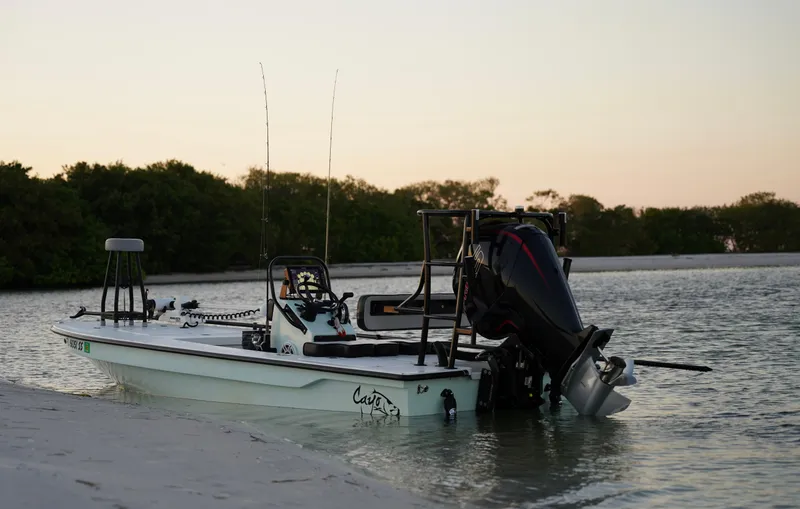 Slide: The Image of 2024 Cayo Boatworks 180 model anchored on a serene shoreline at sunset. - 14