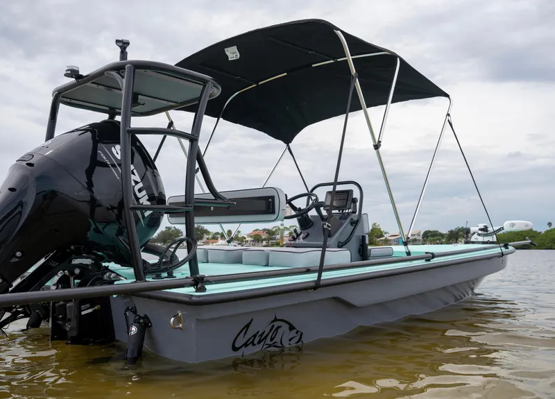 Slide: The Image of 2024 Cayo Boatworks 180 in water with black canopy and Suzuki outboard motor. - 27