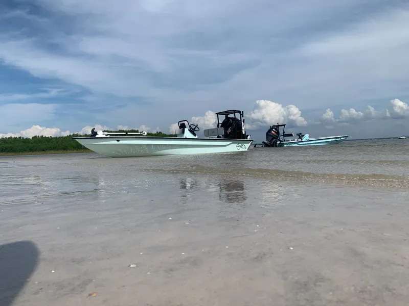 Slide: The Image of 2024 Cayo Boatworks 180 on a sandy shore with another boat in the background. - 4