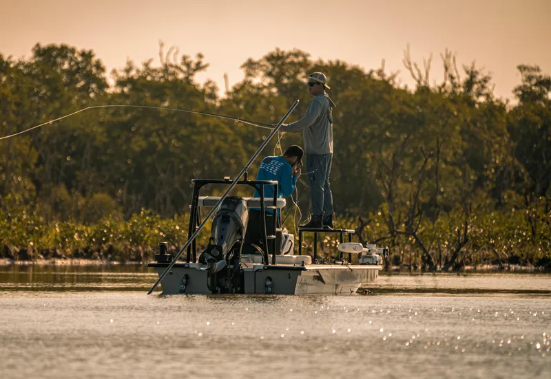 Slide: The Image of 2024 Cayo Boatworks 180 in action, two people fishing in a serene waterway. - 6