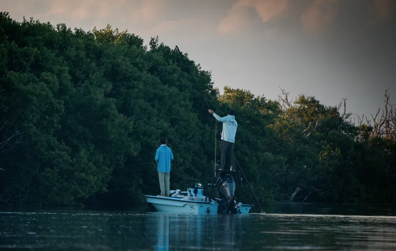 Slide: The Image of Two people fishing on a 2024 Cayo Boatworks 180 in a serene, wooded area. - 8